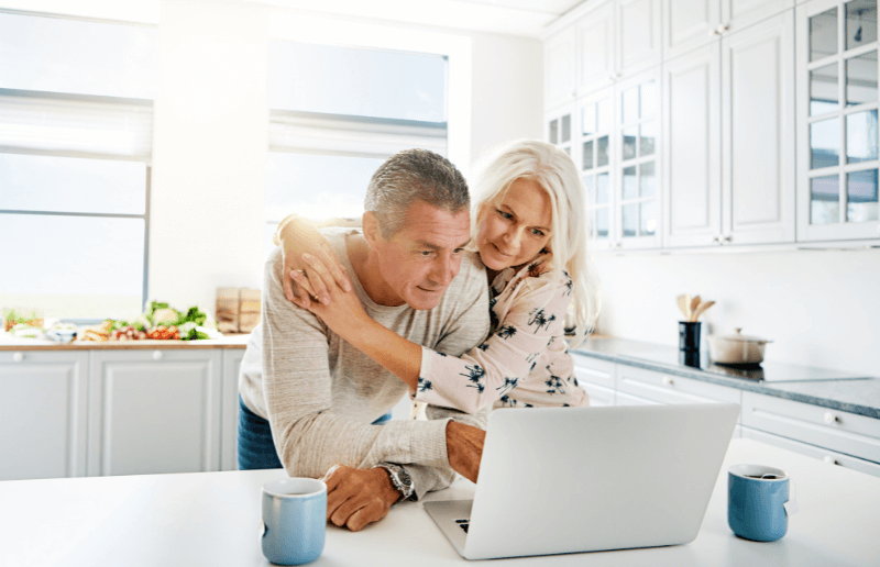 A senior couple of homeowners research on their laptop about the best home buying sites list their house on