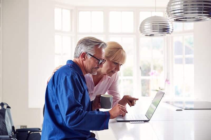 Two elderly homeowners research online if it is a good time to sell a house now